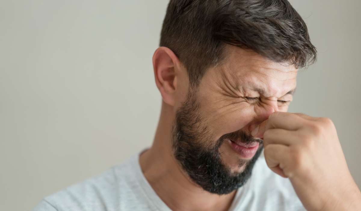 A man plugging his nose to prevent smelling something bad