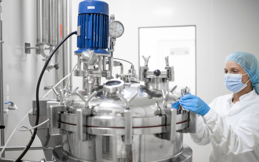 A woman in a clean suit and mask standing next to a medical grade chilling device